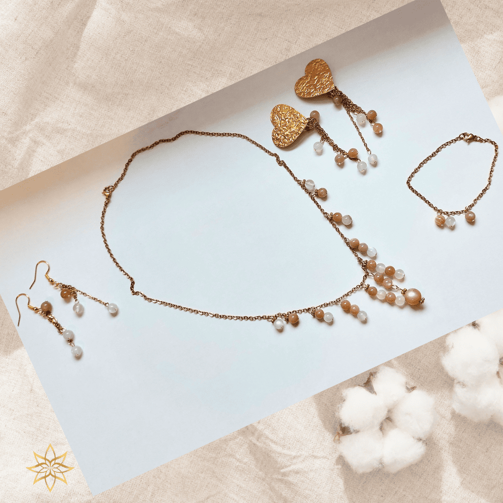 La parure Lune de miel est une ode à la douceur, à la féminité et à l’intuition. Inspirée par l’énergie apaisante de la lune, elle a été créée comme un bijou-talisman, pensé pour accompagner les femmes dans leur sensibilité, leur équilibre émotionnel et leur reconnexion intérieure. Composée d’un collier, d’un bracelet et de deux paires de boucles d’oreilles (dont une version à clips pour oreilles non percées), cette parure associe la pierre de lune naturelle à l’élégance lumineuse de l’acier inoxydable doré.